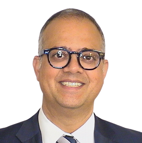 Portrait Of Mature Male Doctor Wearing White Coat Standing In Hospital Corridor