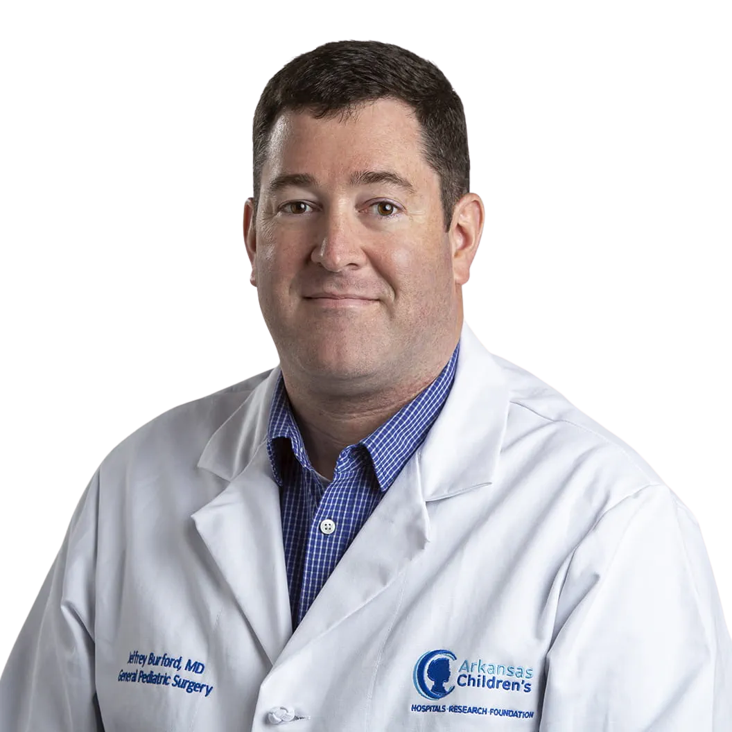 Portrait Of Mature Male Doctor Wearing White Coat Standing In Hospital Corridor