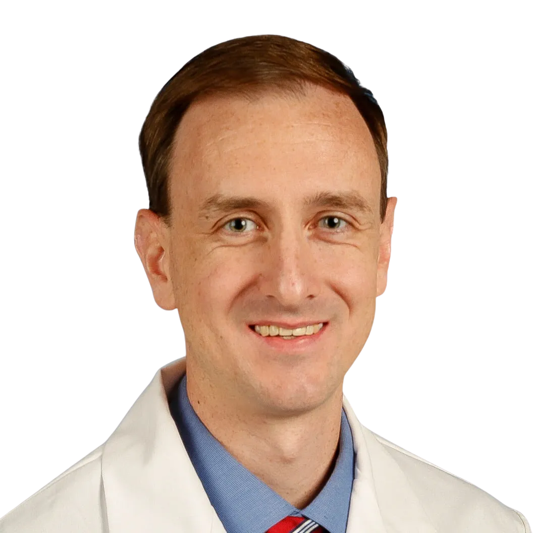 Portrait Of Mature Male Doctor Wearing White Coat Standing In Hospital Corridor