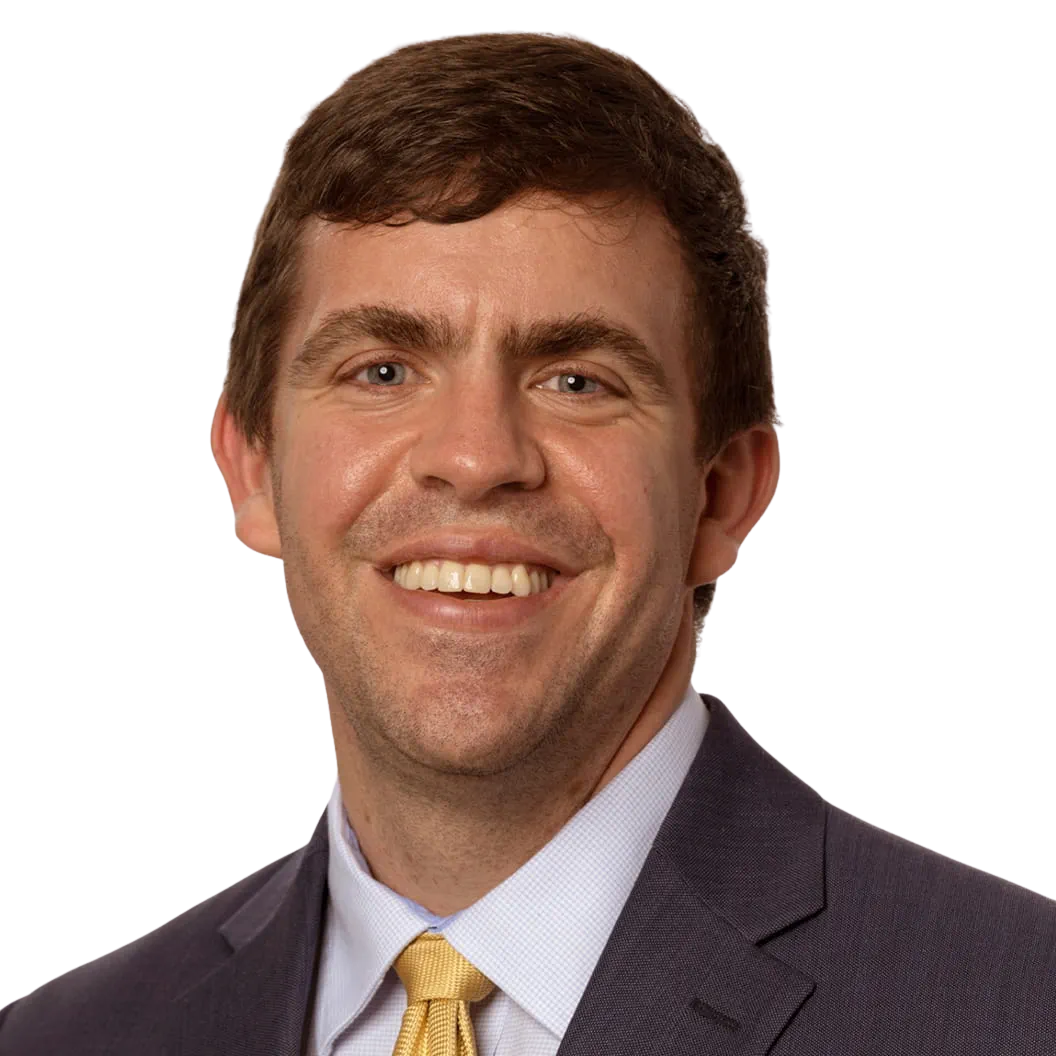 Portrait Of Mature Male Doctor Wearing White Coat Standing In Hospital Corridor