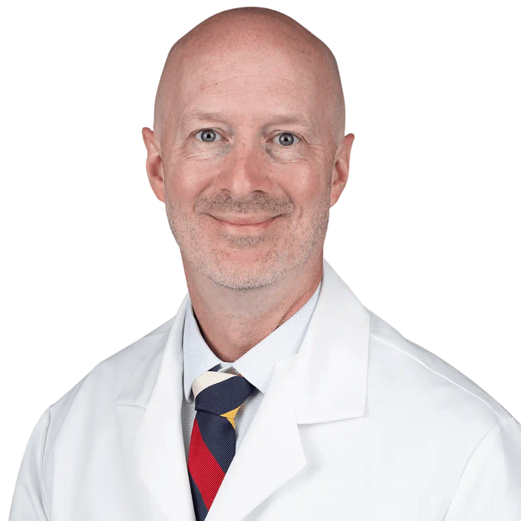 Portrait Of Mature Male Doctor Wearing White Coat Standing In Hospital Corridor