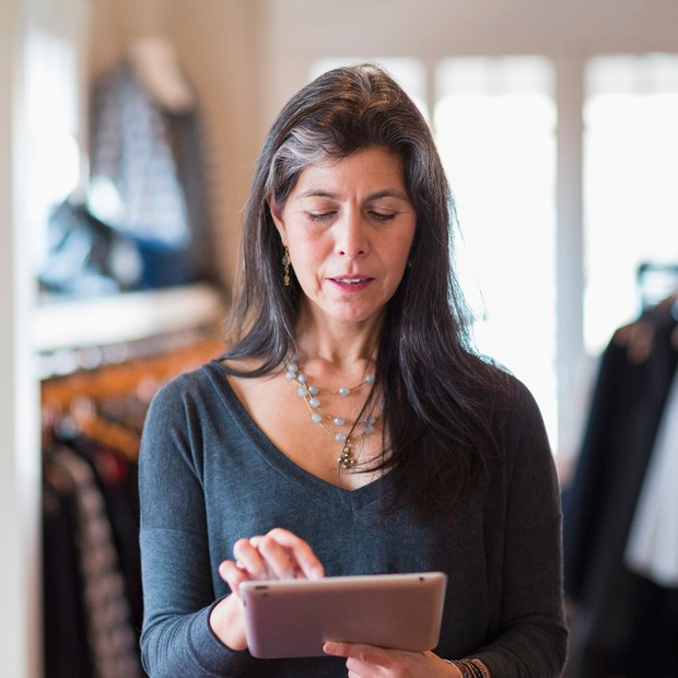 woman standing in clothing store holding tablet
