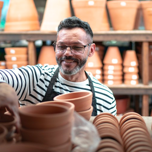 man with striped shirt organizing terracotta pots on shelves