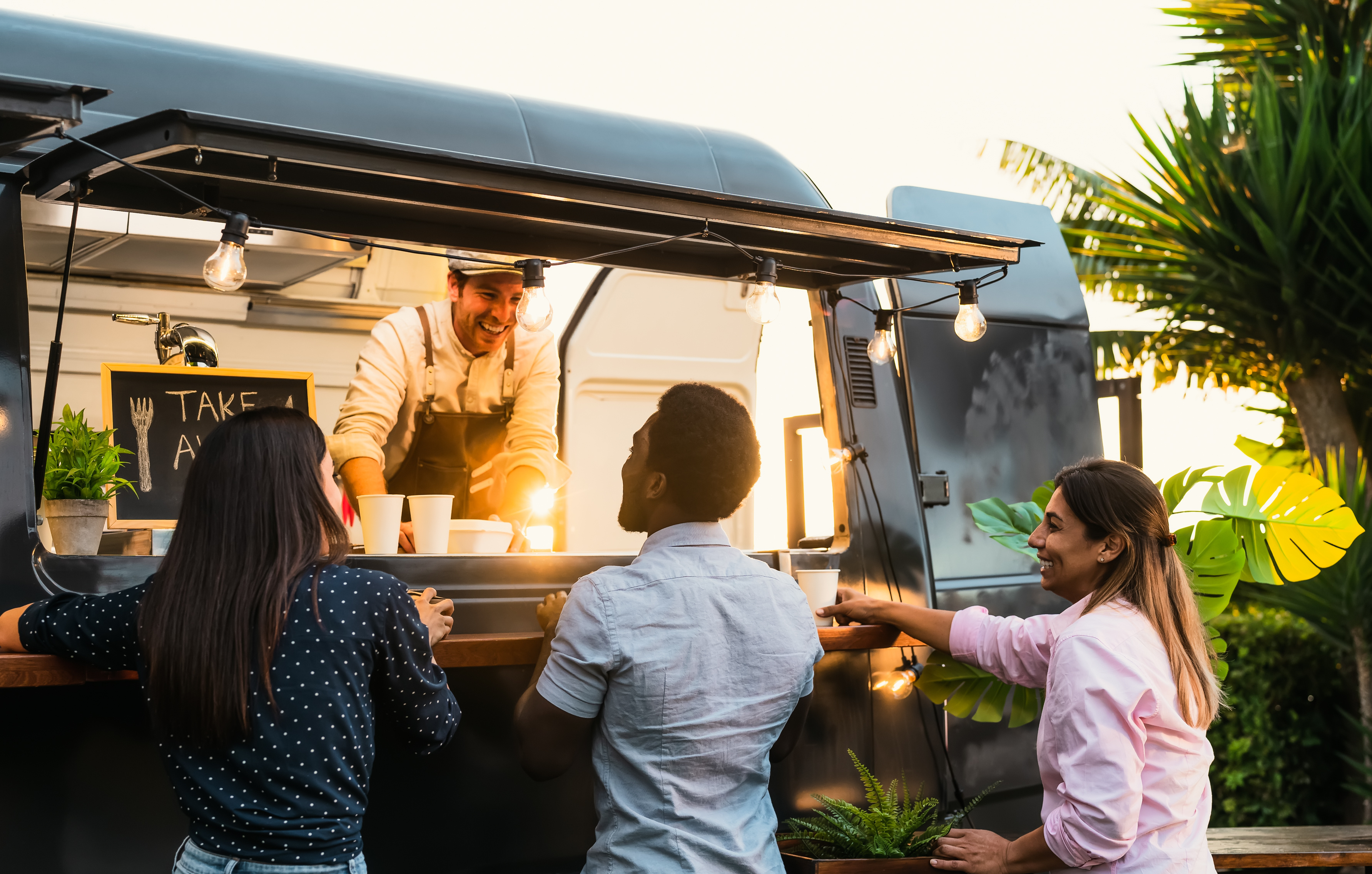 food truck at sunset with three people ordering food at the window