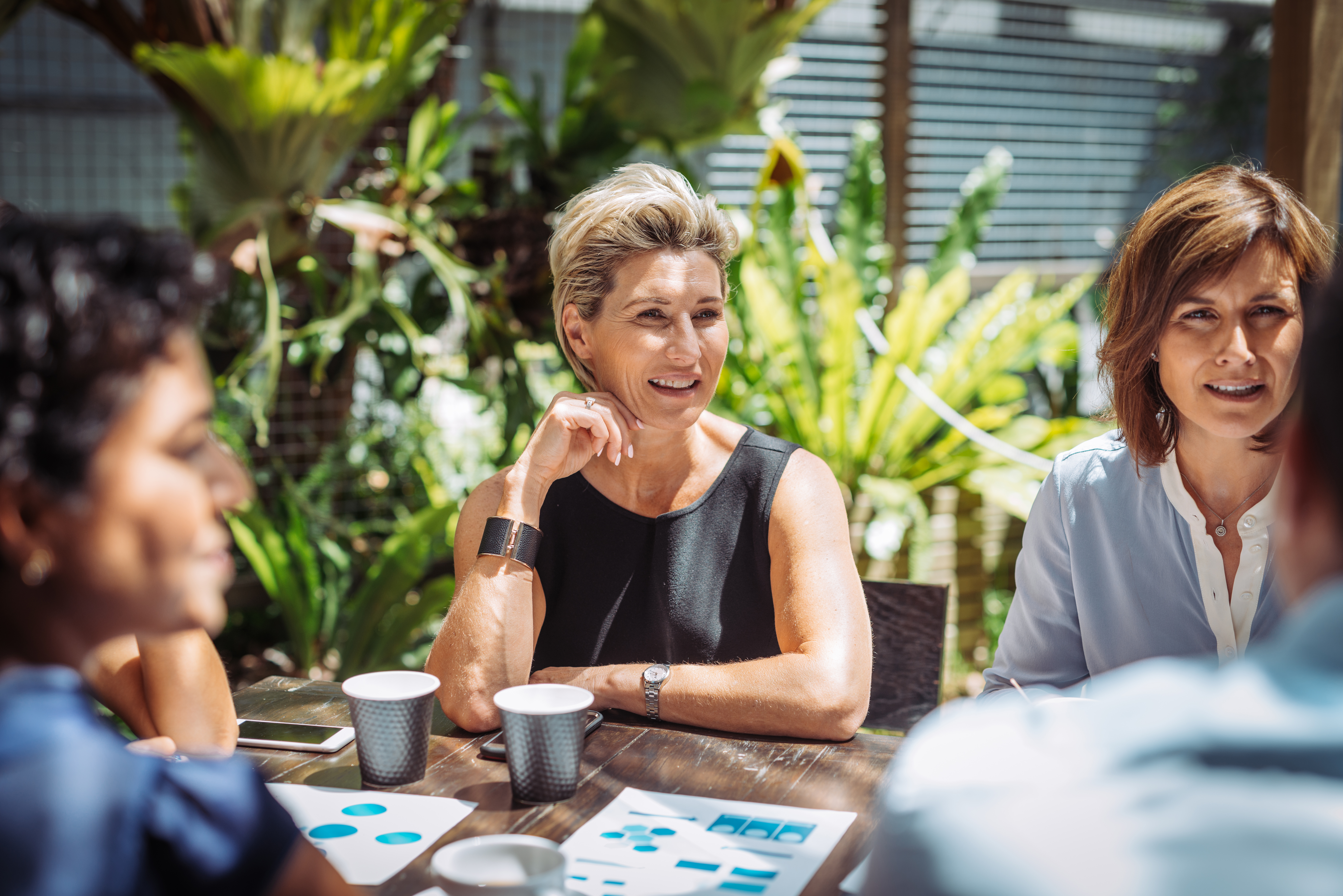 Woman sat at a table outdoors having a meeting with colleagues