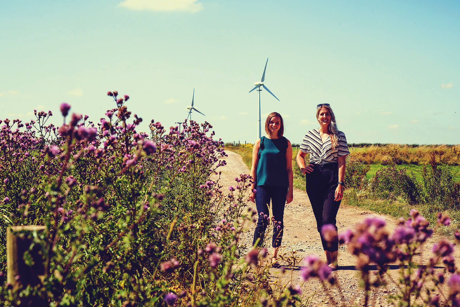 Helen Melling and Clare Davey stood in a field in front of wind turbines renewable energy