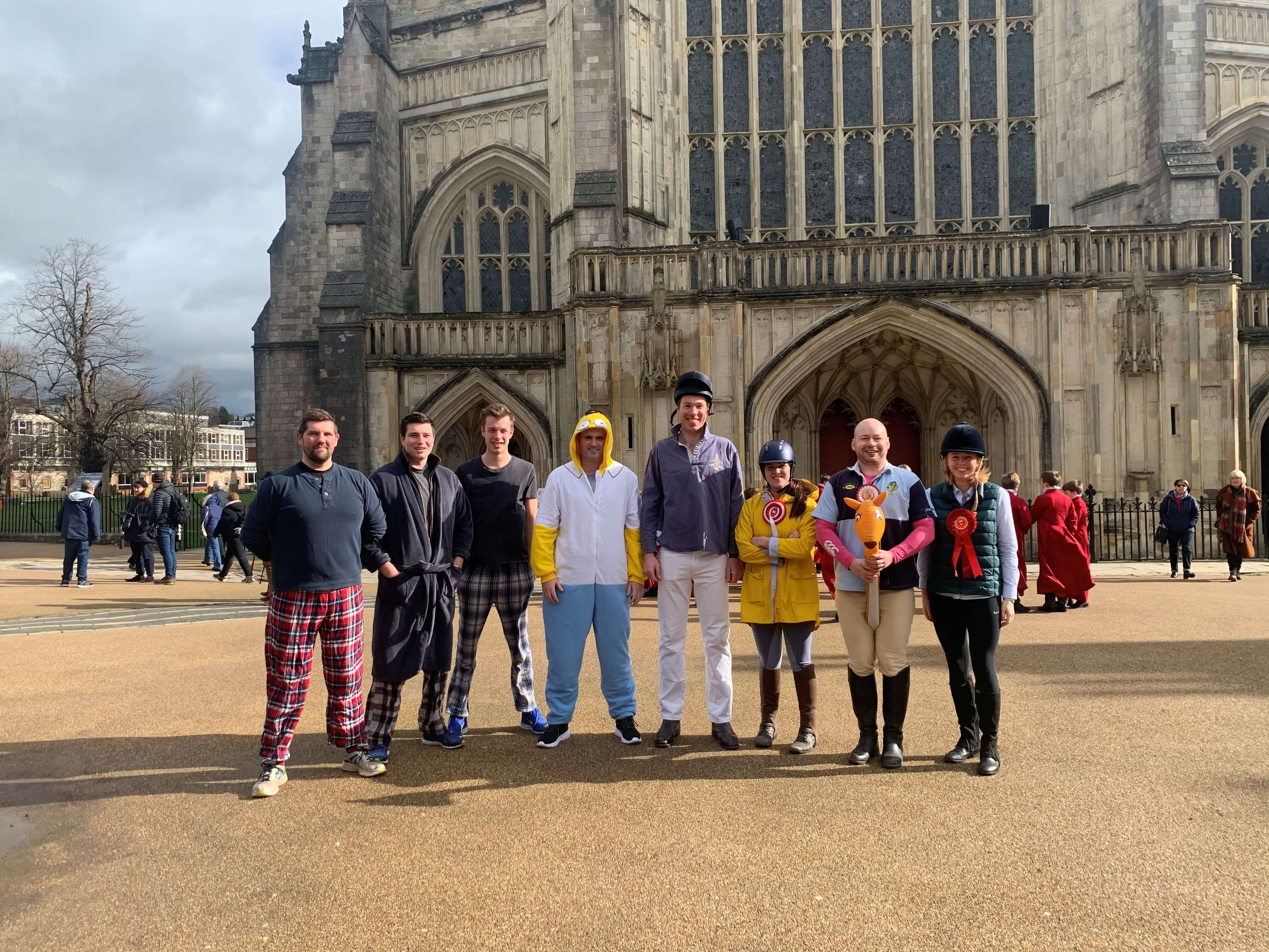 Photograph of Carter Jonas team from Winchester office standing in front of Winchester Cathedral after annual pancake race.