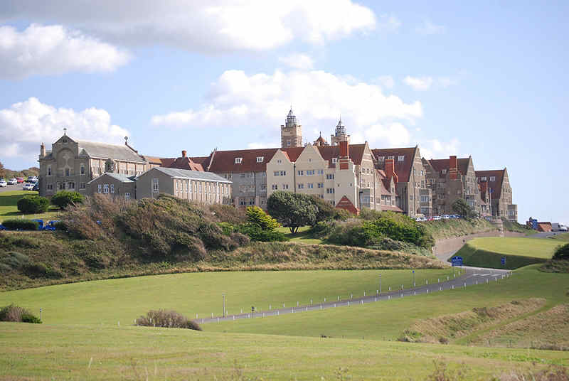 Image of Roedean School in Brighton surrounded by blue sky, clouds and field.