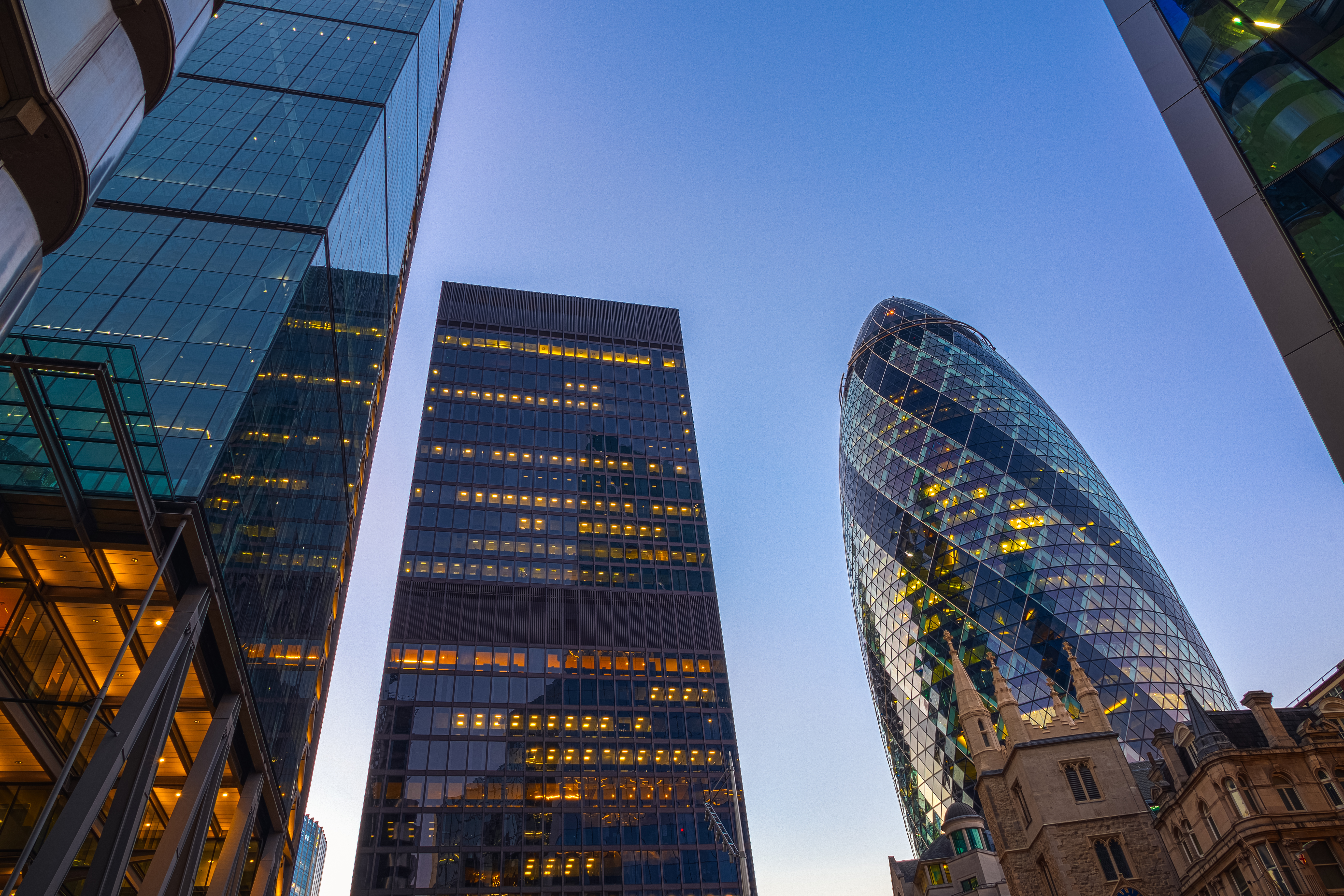 Low angle view of illuminated skyscrapers in the city of London at evening