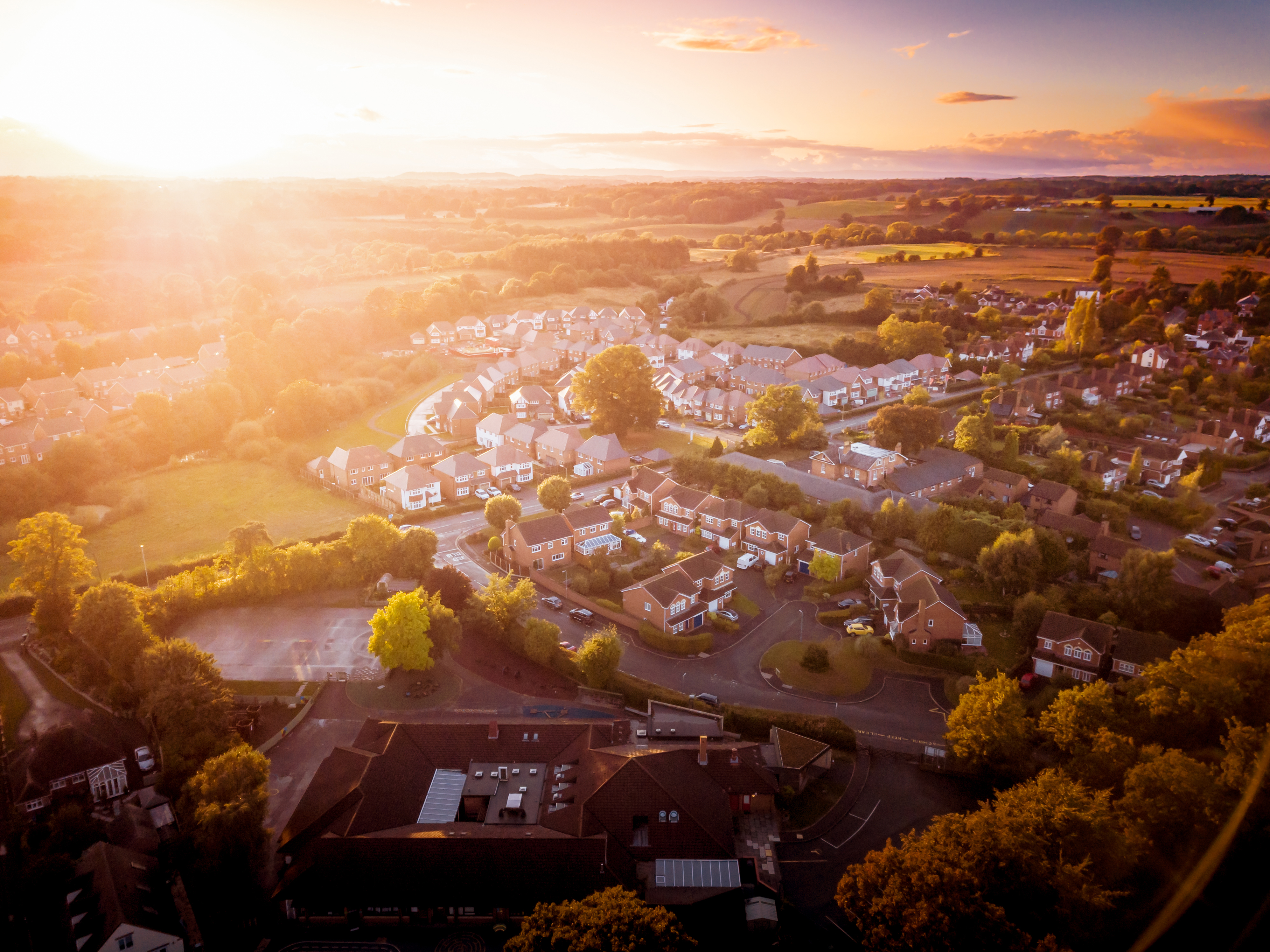 Dramatic, warm lighting creates a homely mood. Very typically English houses that are over 100 years old. A picturesque scene, created by the long shadows and warm glow.