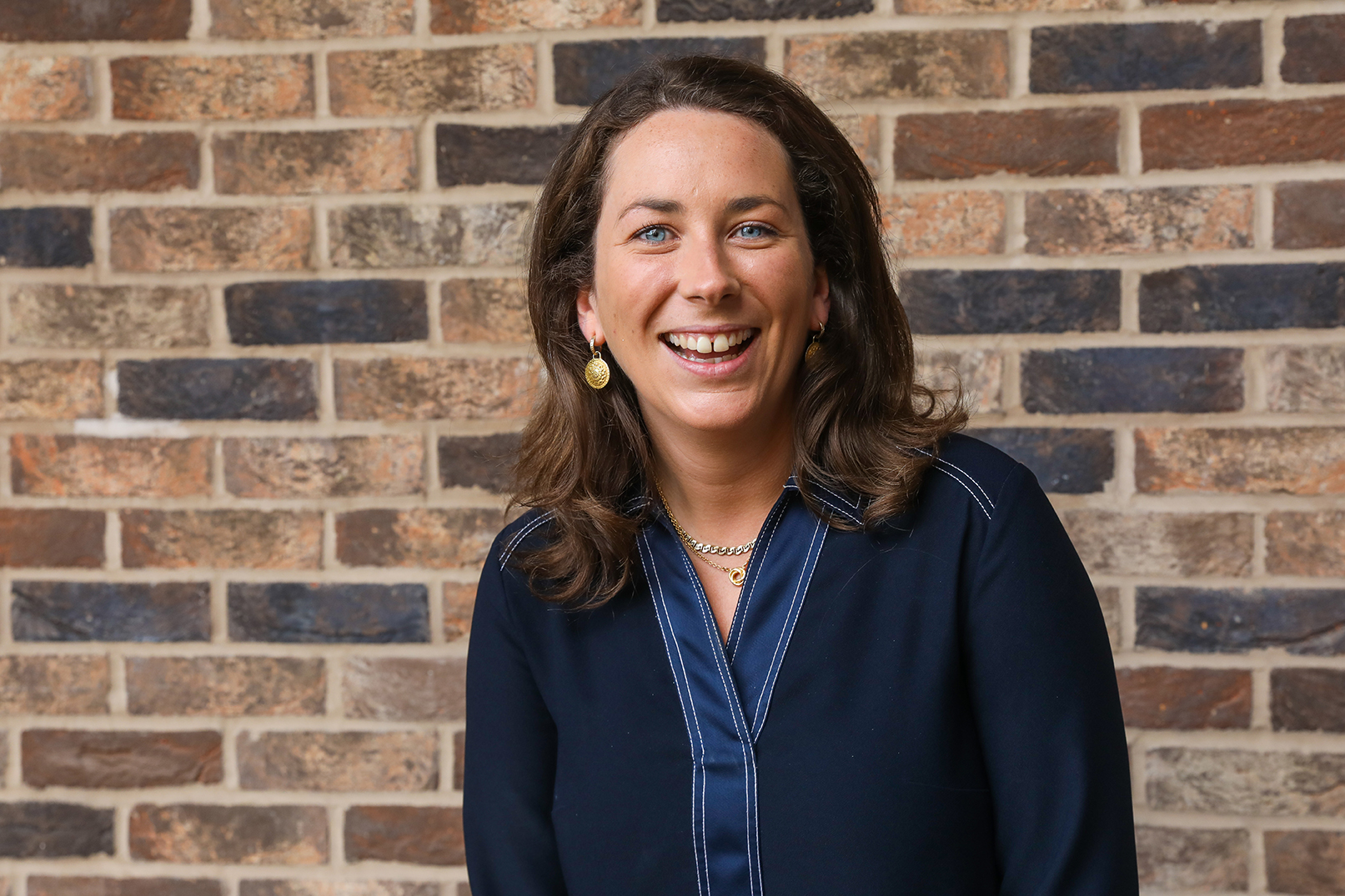 A picture of Rebecca D'Erlanger, Investment Analyst smiling and laughing stood in front of a beautiful classic brick wall