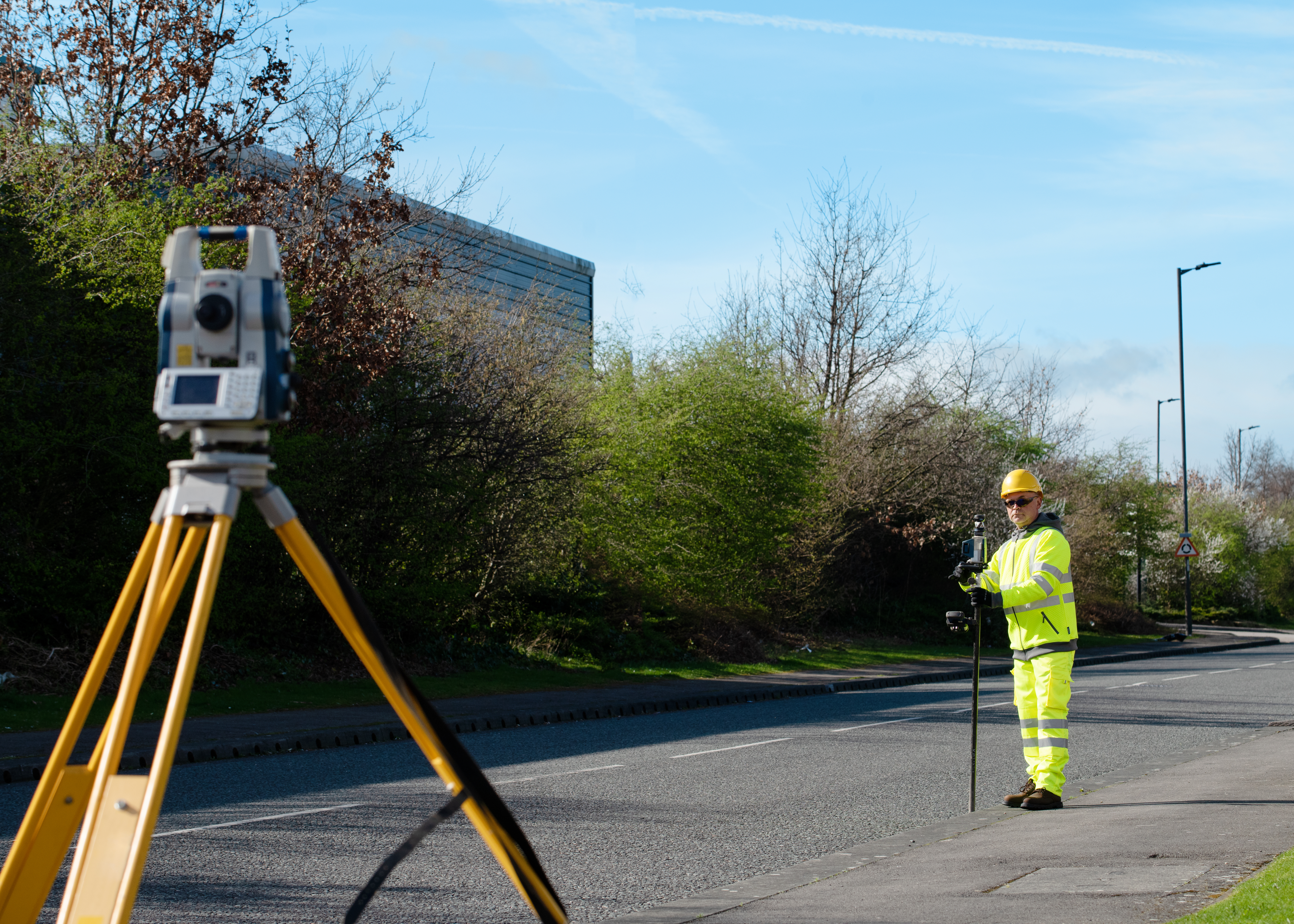 Surveyor doing road survey using modern robotic total station EDM before begining of construction works and setting construction site
