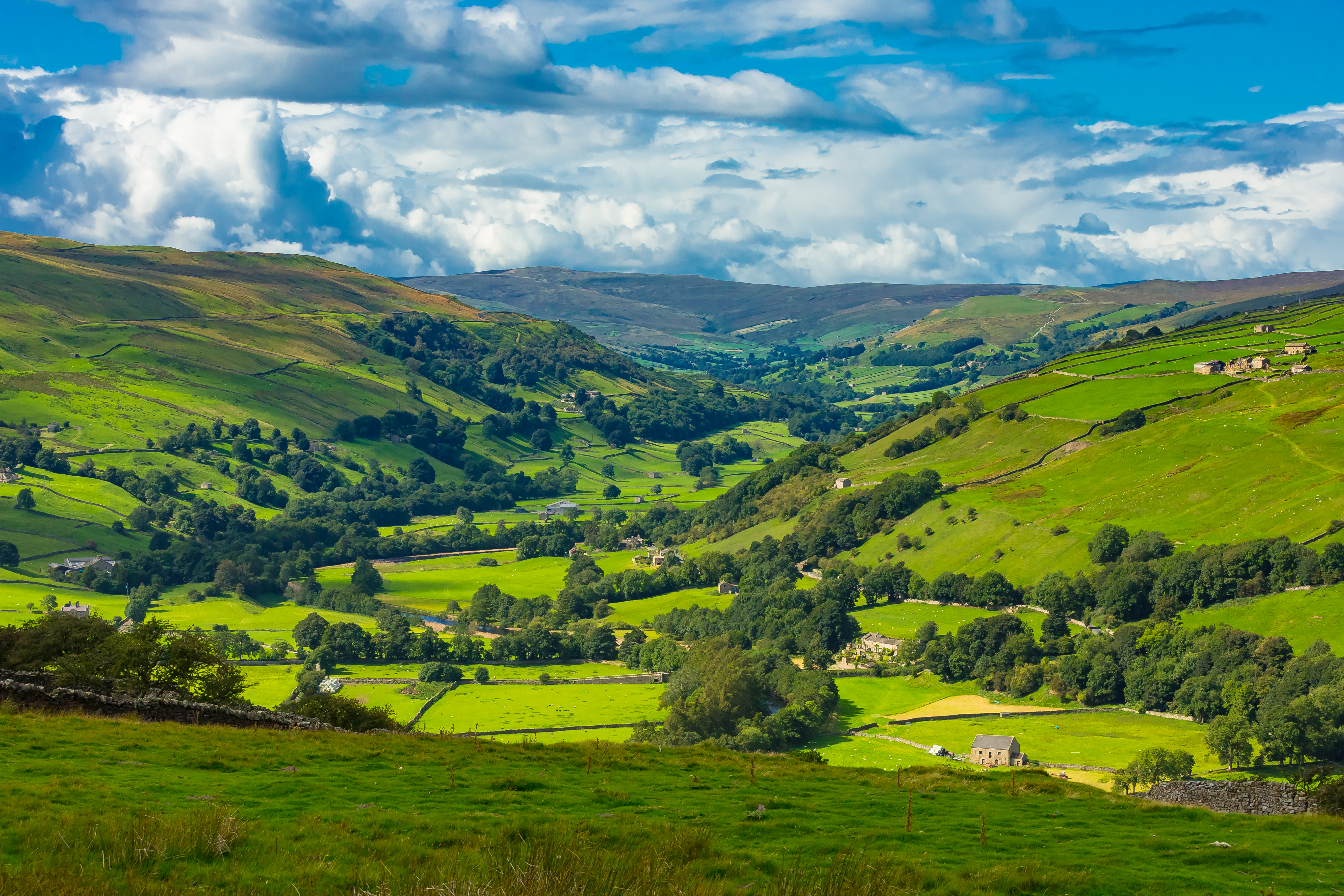 The Yorkshire Dales.  Askrigg road to Gunnerside in Swaledale.  Farmsteads, drystone walling, fields and meadows with the River Swale running through it.  Horizontal.  Space for copy.