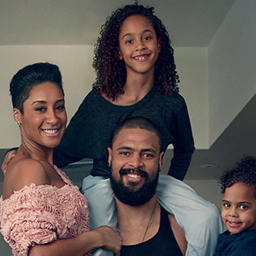 family smiling, looking at the camera.