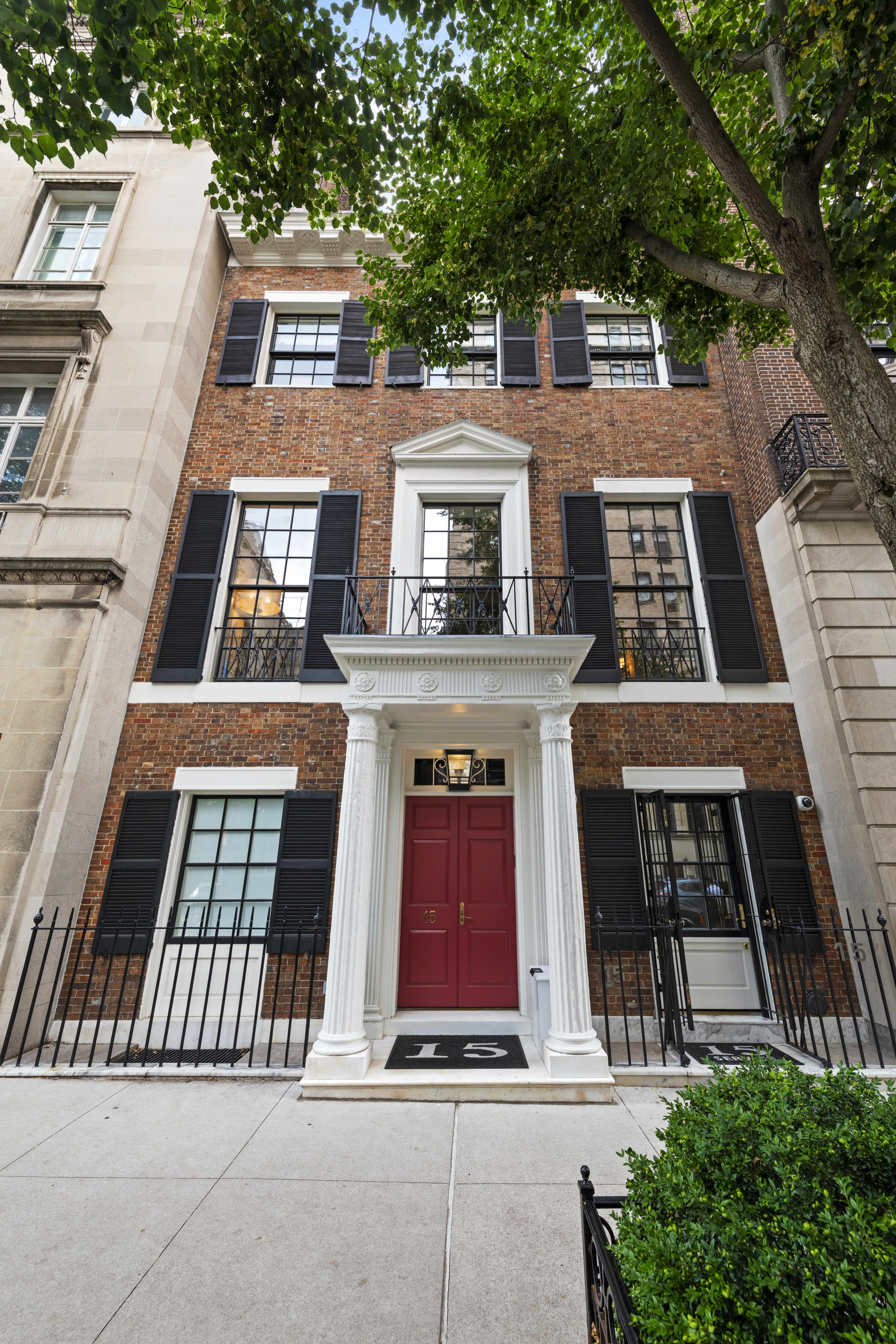 Luxurious living room featuring ornate ceiling murals, a central fireplace with a framed painting above, and modern white and gray sofas arranged around a black coffee table, illuminated by large windows.