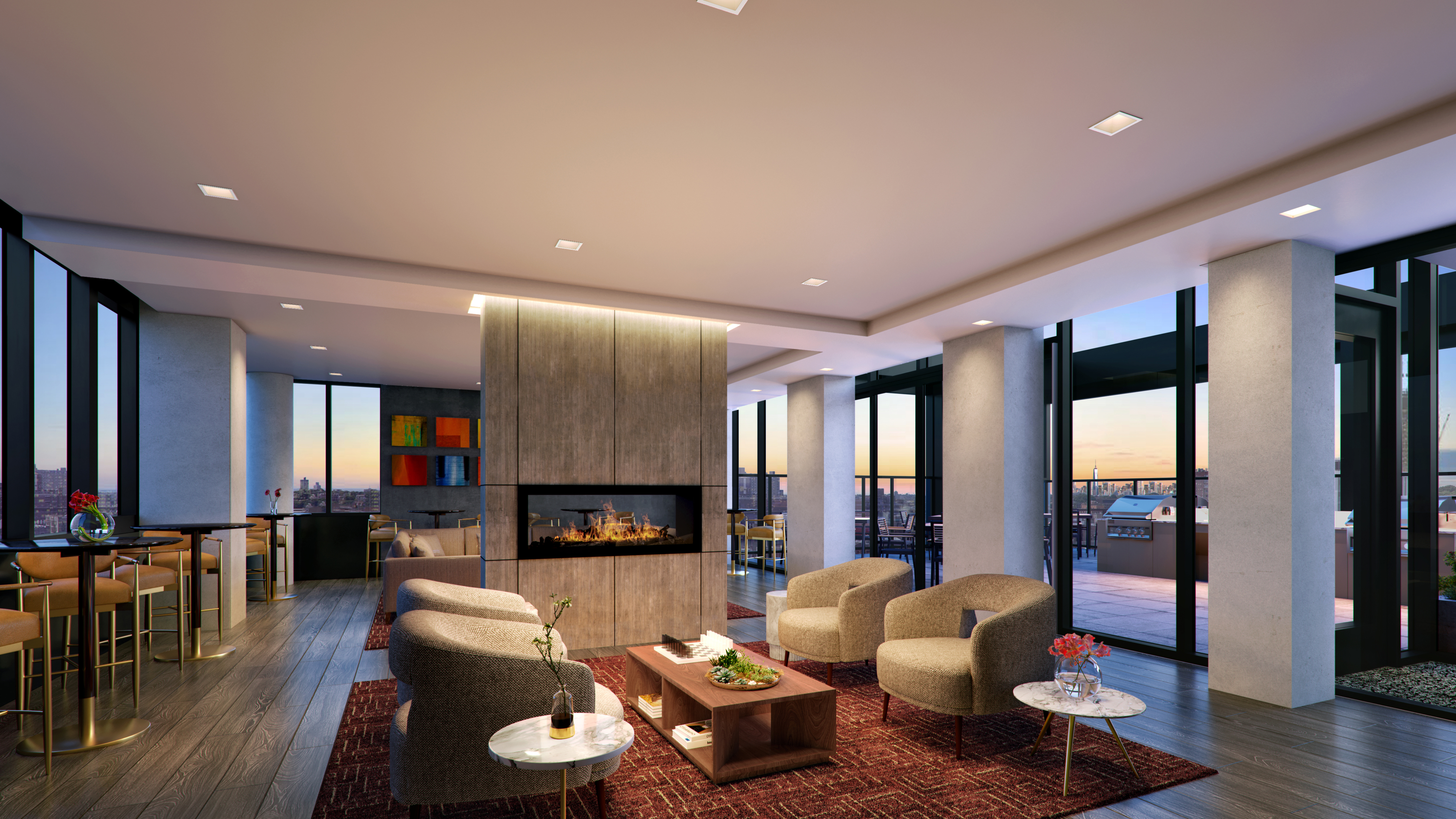 A modern, spacious living room with large windows showcasing a sunset view. The room features a central fireplace, four beige armchairs around a wooden coffee table, and two small round side tables with decorative items.
