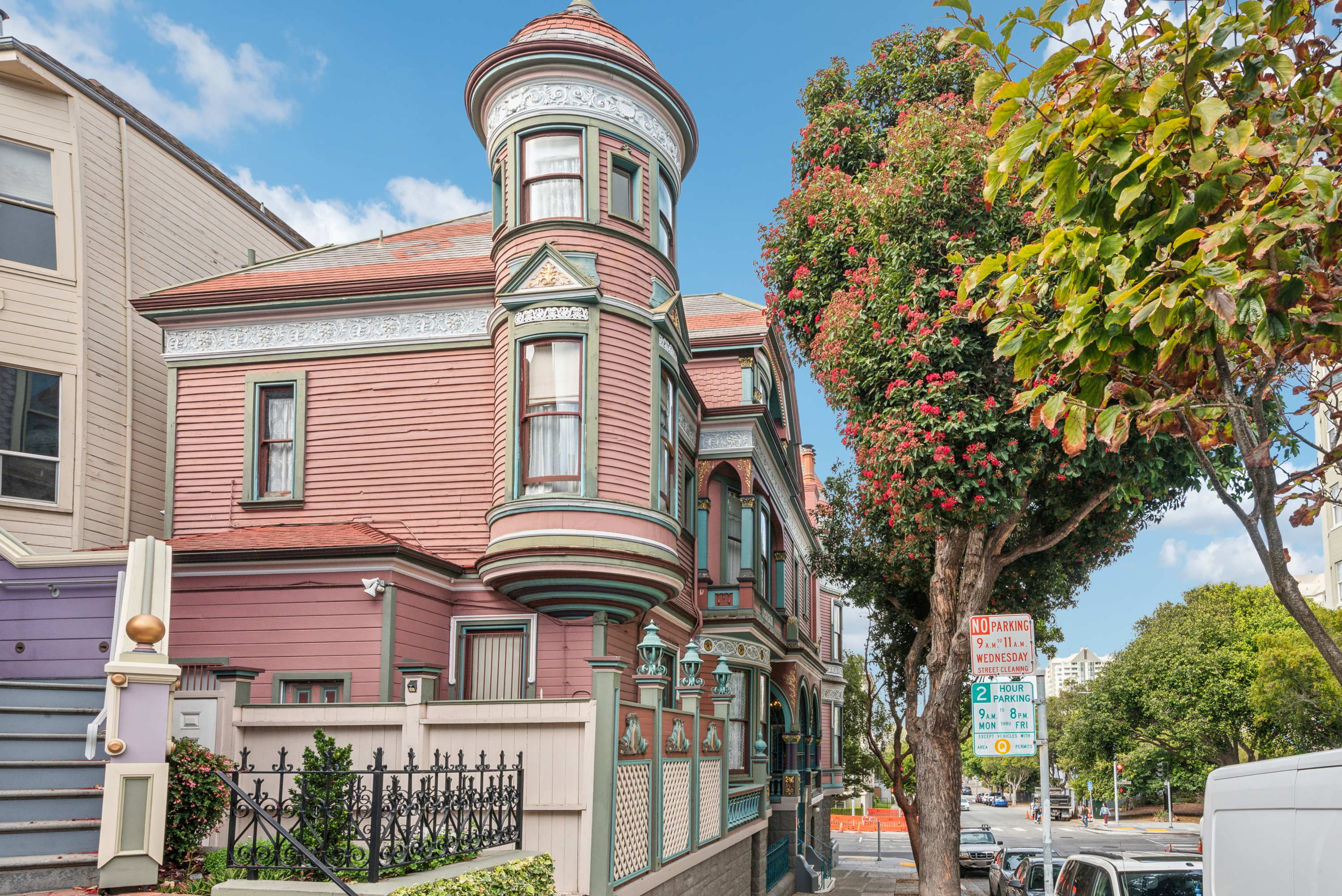 Outside of a Victorian house, clad in pink and green shingles.