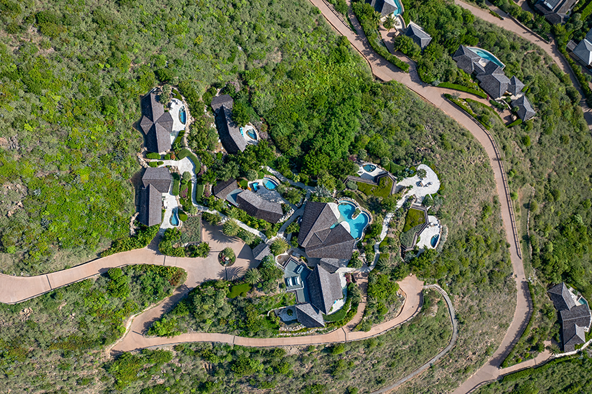 Aerial view of luxury homes with pools and greenery.