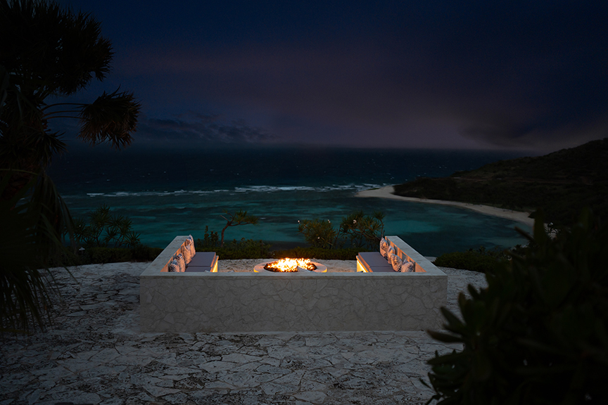 Outdoor fire pit with seating by the water at night.