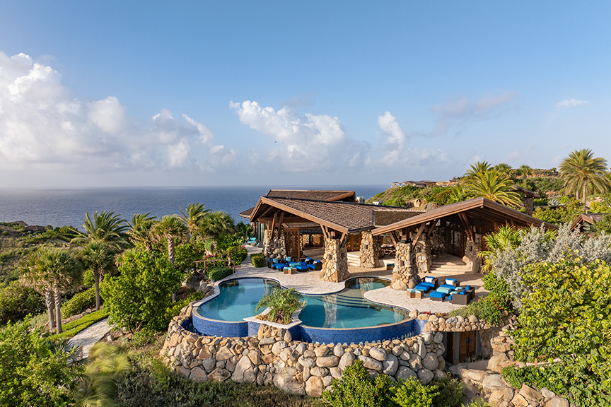Villa with infinity pool, ocean view, and tropical greenery.