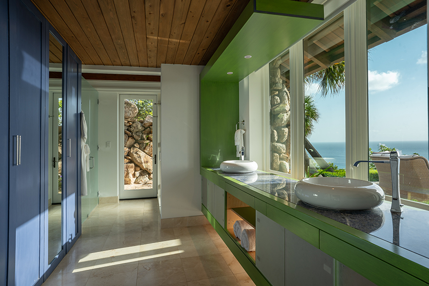 Modern bathroom with blue-green cabinets, vessel sinks, ocean view, and wooden ceiling.