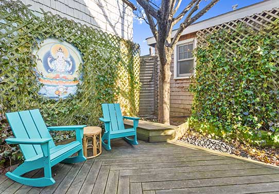 Cozy patio with turquoise chairs and ivy-covered walls.