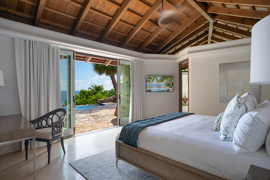 Bedroom with pool view, wooden ceiling, and white decor.