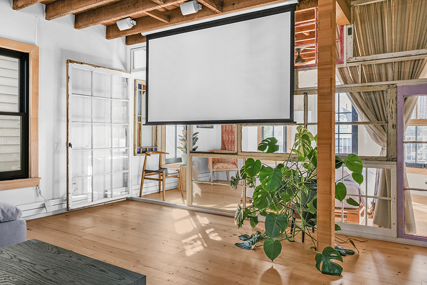 Bright modern living space with wood beams, projector screen, and glass partition.

