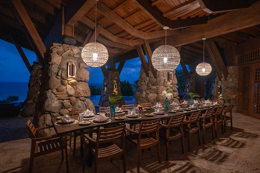 Outdoor dining table under pavilion with ocean view.