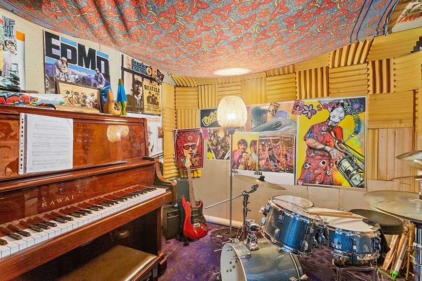 Music room with piano, drums, guitar, and posters.


