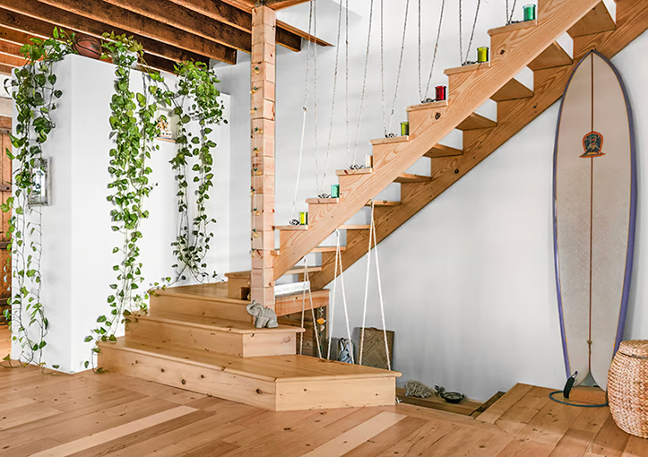 Wooden staircase with plants and surfboard.
