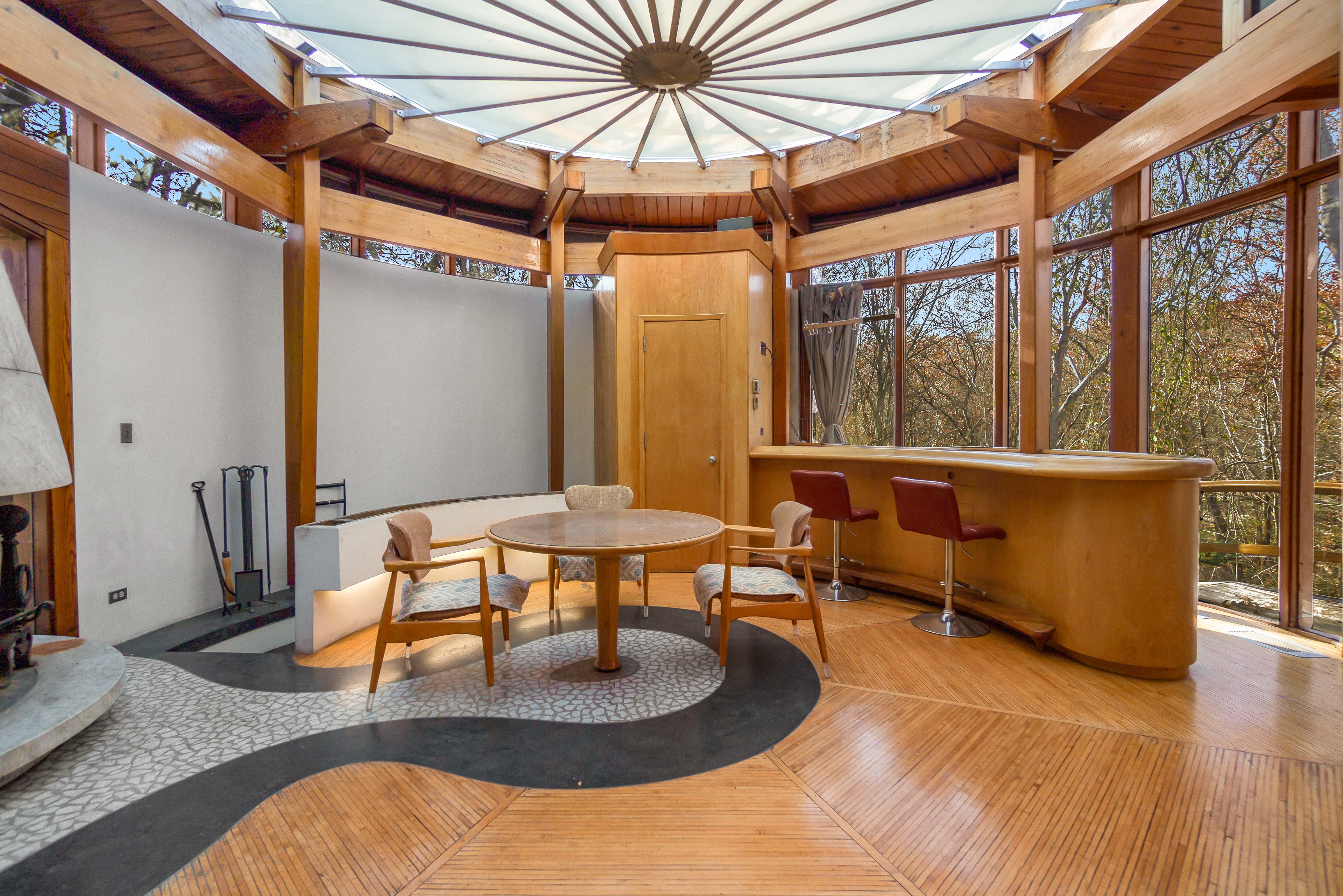 Modern dining room with a wooden table, white chairs, chandelier, and large window.