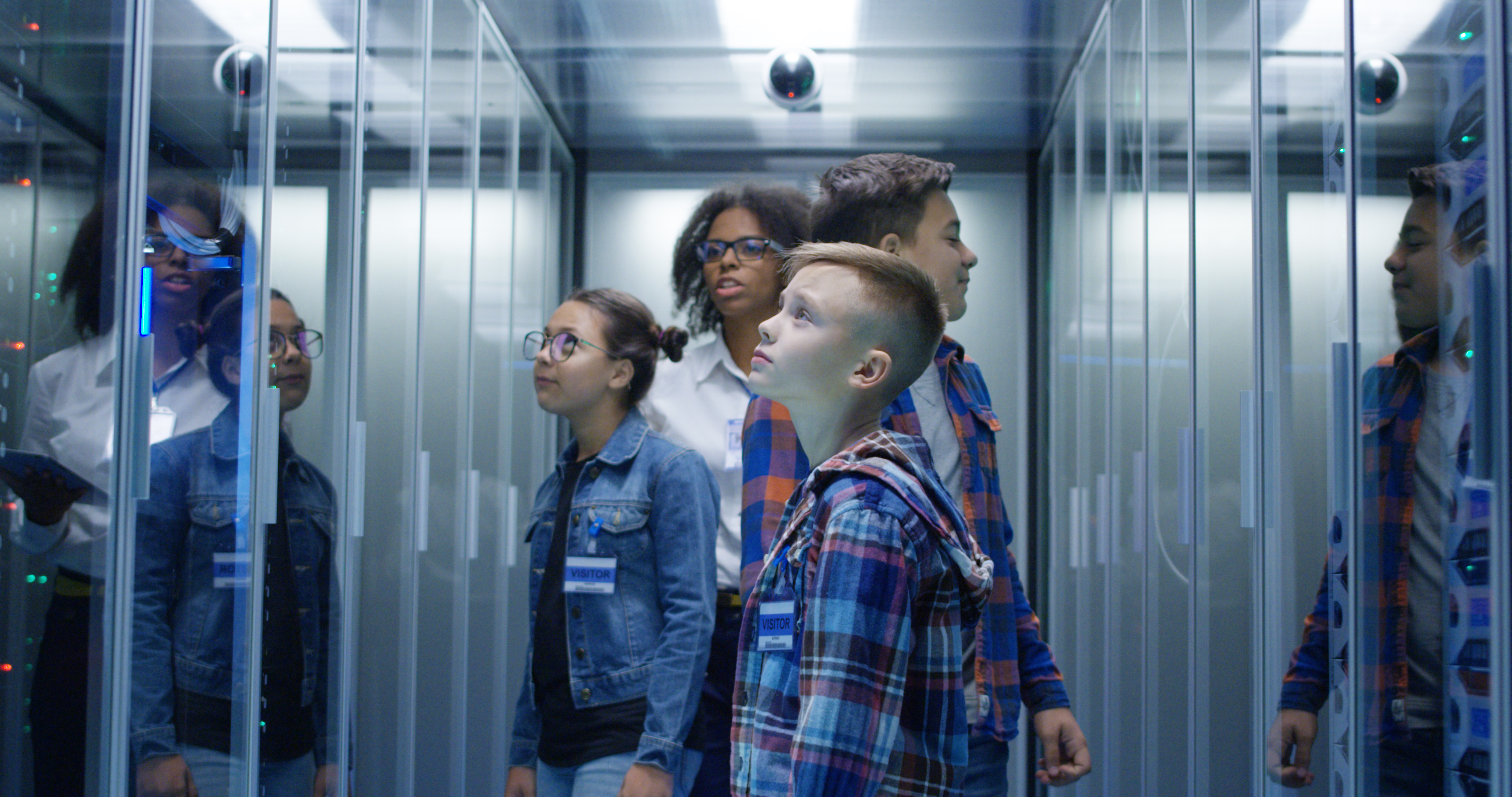 Medium shot of a young female technician showing around children in server park