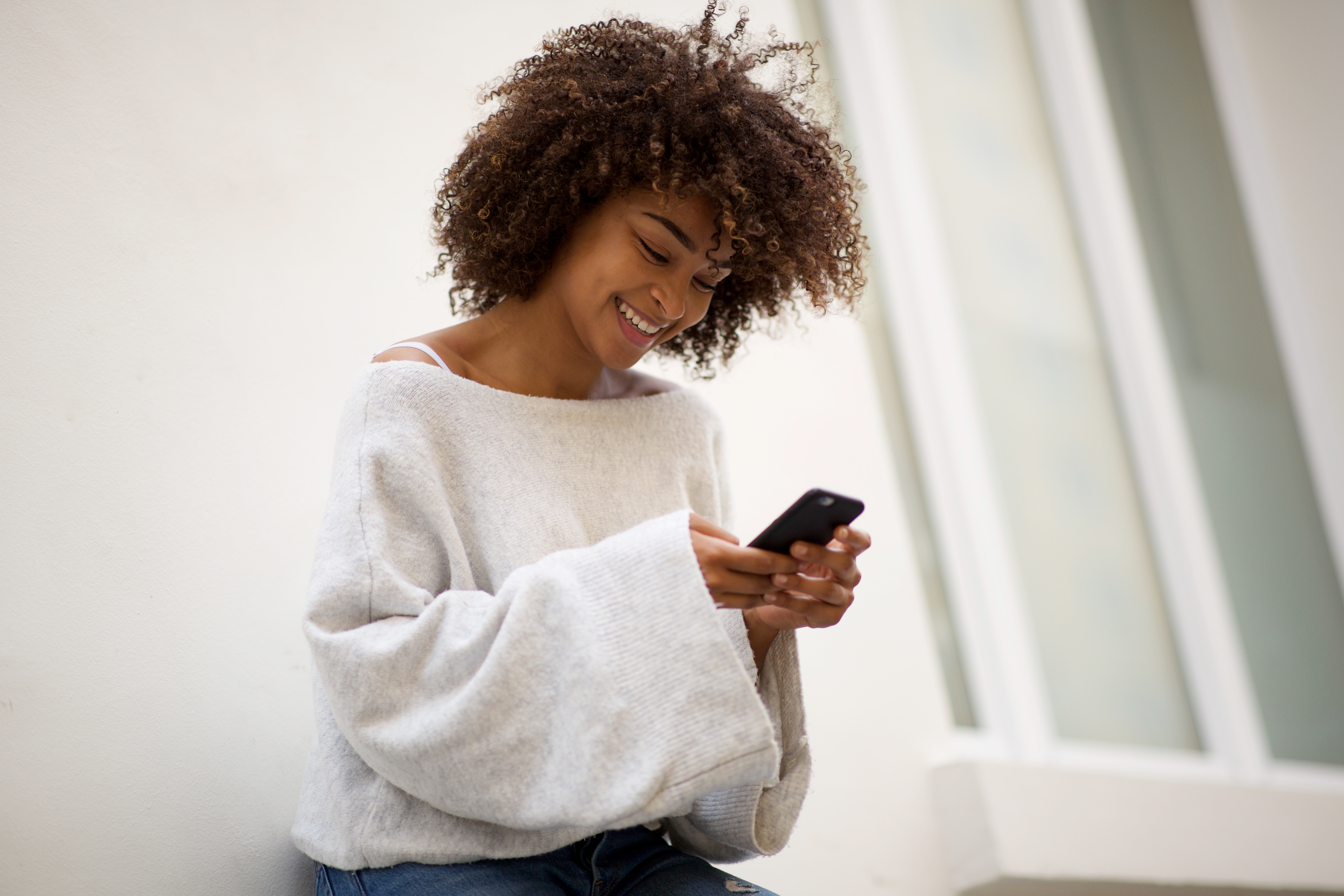 smiling young african american woman looking at phone