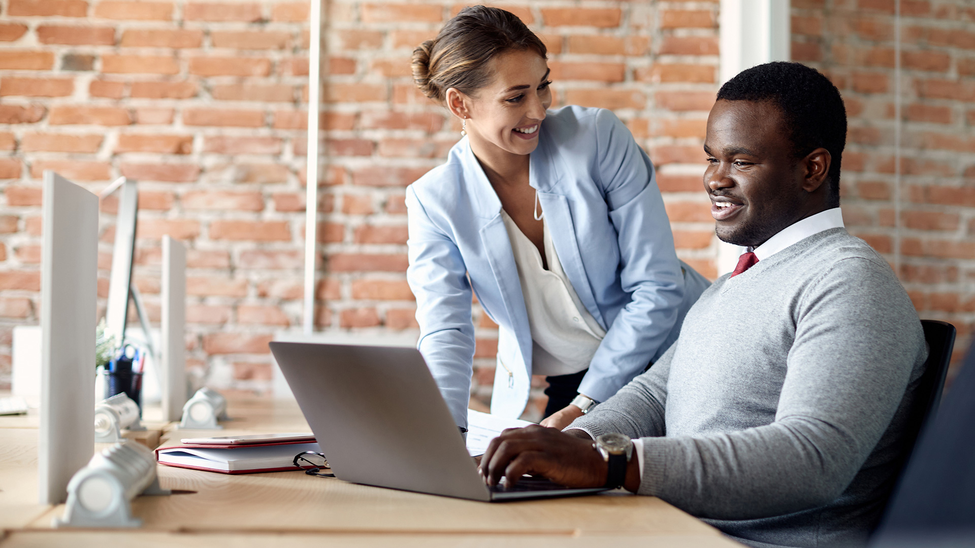 Happy coworkers collaborate using laptop computer