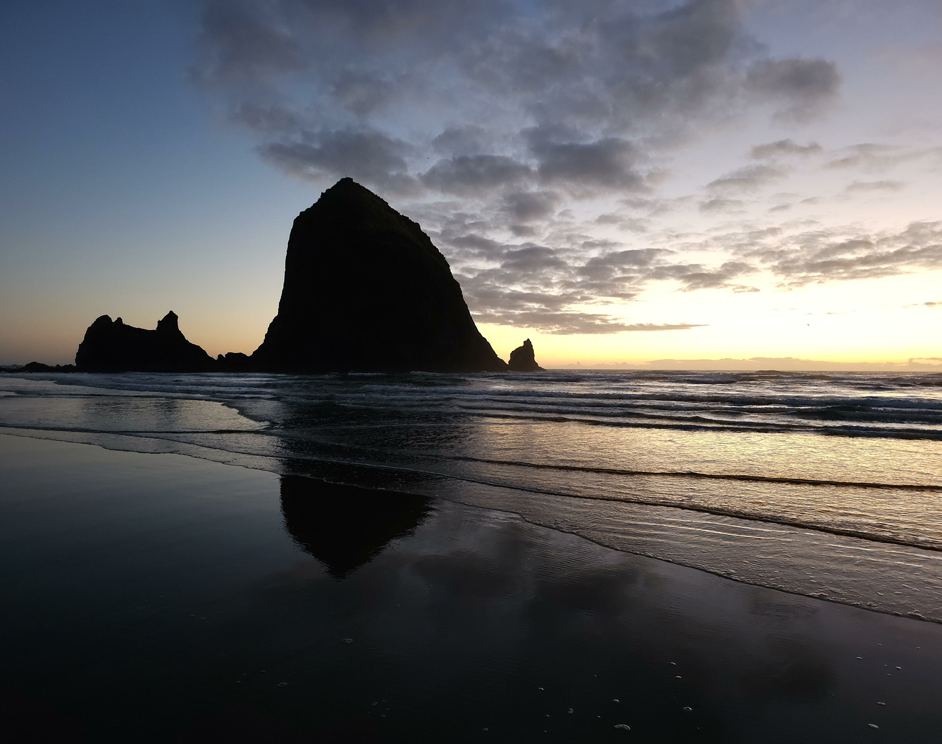 Beach at sunset -  calm sea with island outcrops in silhouette.