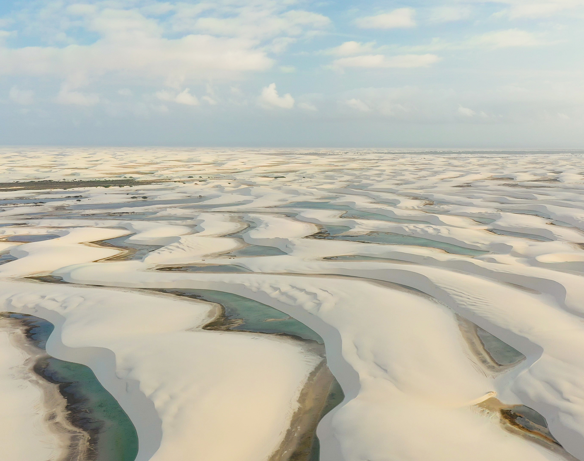 Waves of white sand and water while the tide is out on a beach