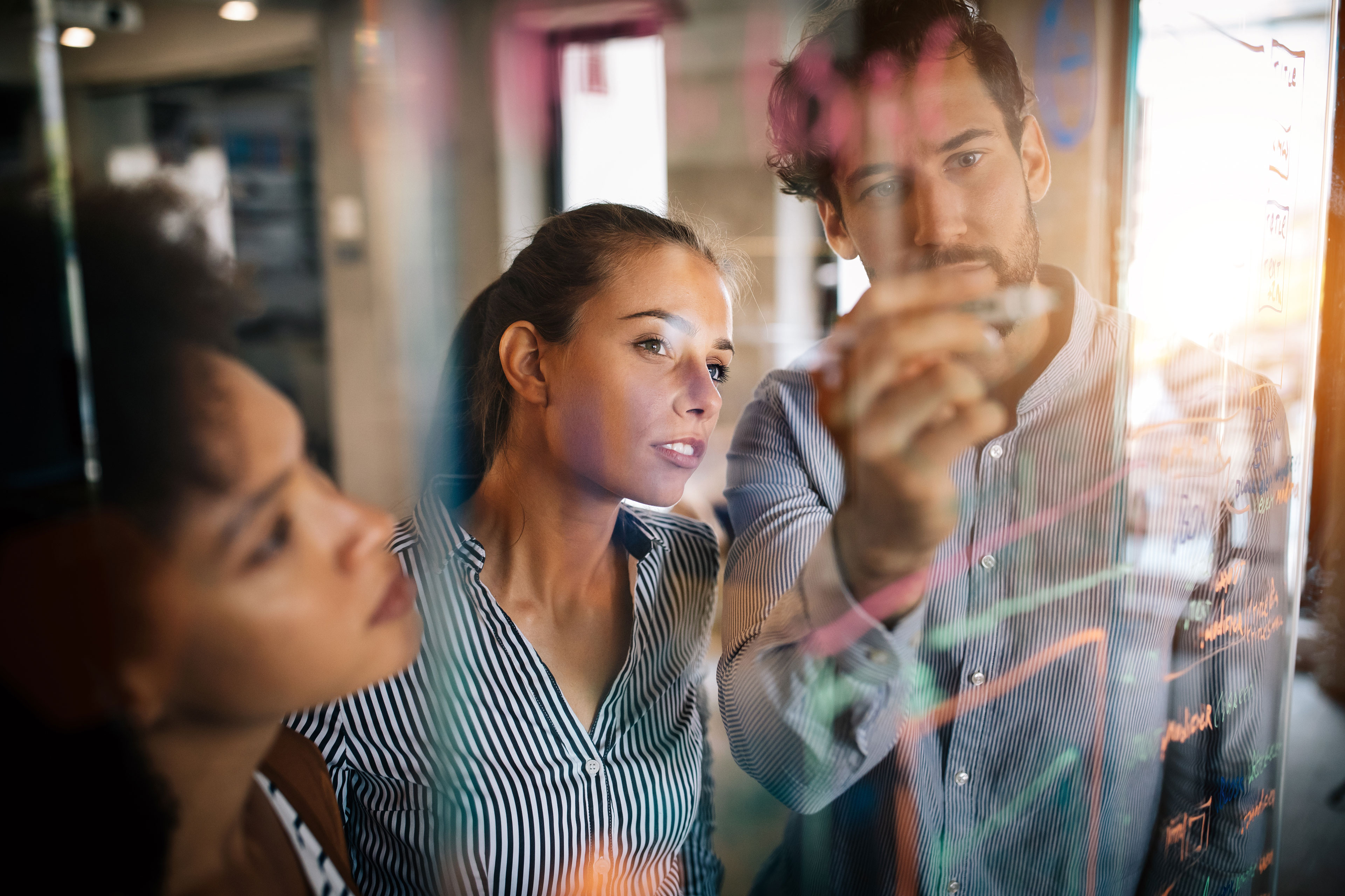 an image of data analysts collaborating and problem solving together at a marker board