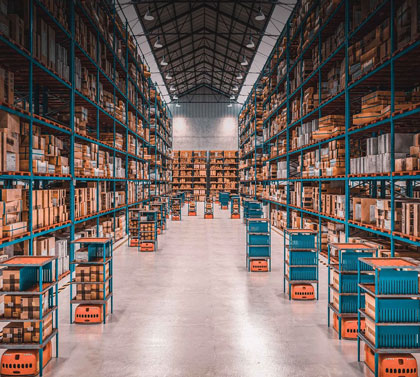A one point perspective image looking down a row of shelves stacked with large boxes in a warehouse
