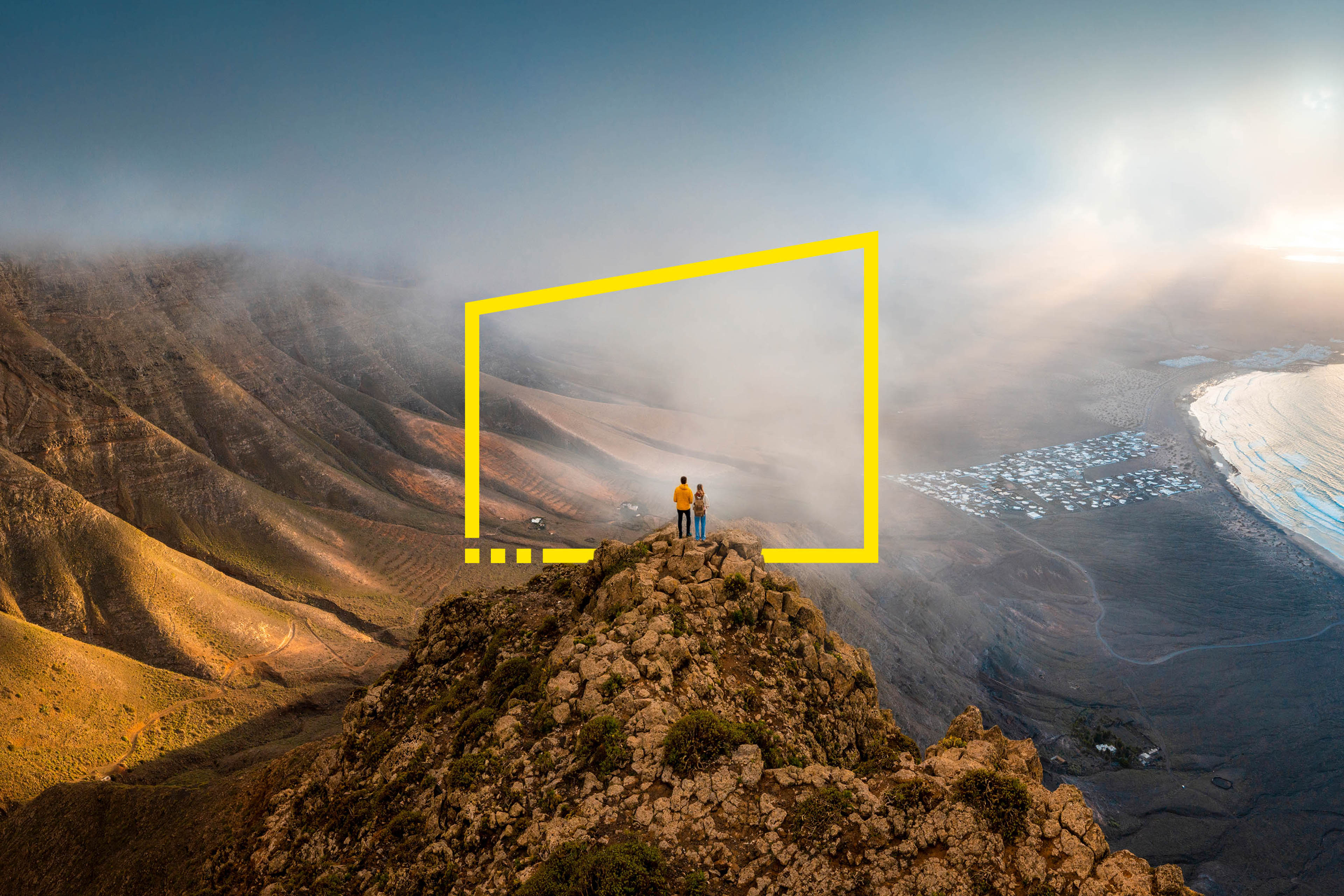 An image of a couple standing on top of a cliff looking at a sunset in Lanzarote, Spain
