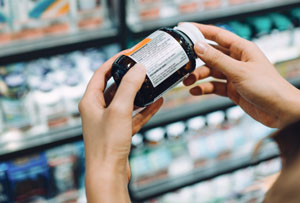 A close up image of a person's hands holding a pill bottle and reading the label