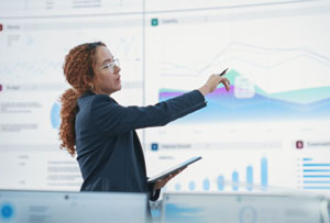 An image of a businesswoman giving a presentation using visual aids behind her