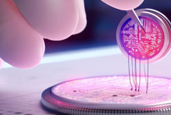 A close-up image of a hand holding a microchip with a two prong instrument 