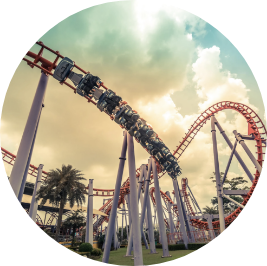 Image looking up at a swirling roller coaster with cloudy sky background