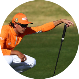 Image of professional golfer, Rickie Fowler, squatting on golf course and strategizing next shot