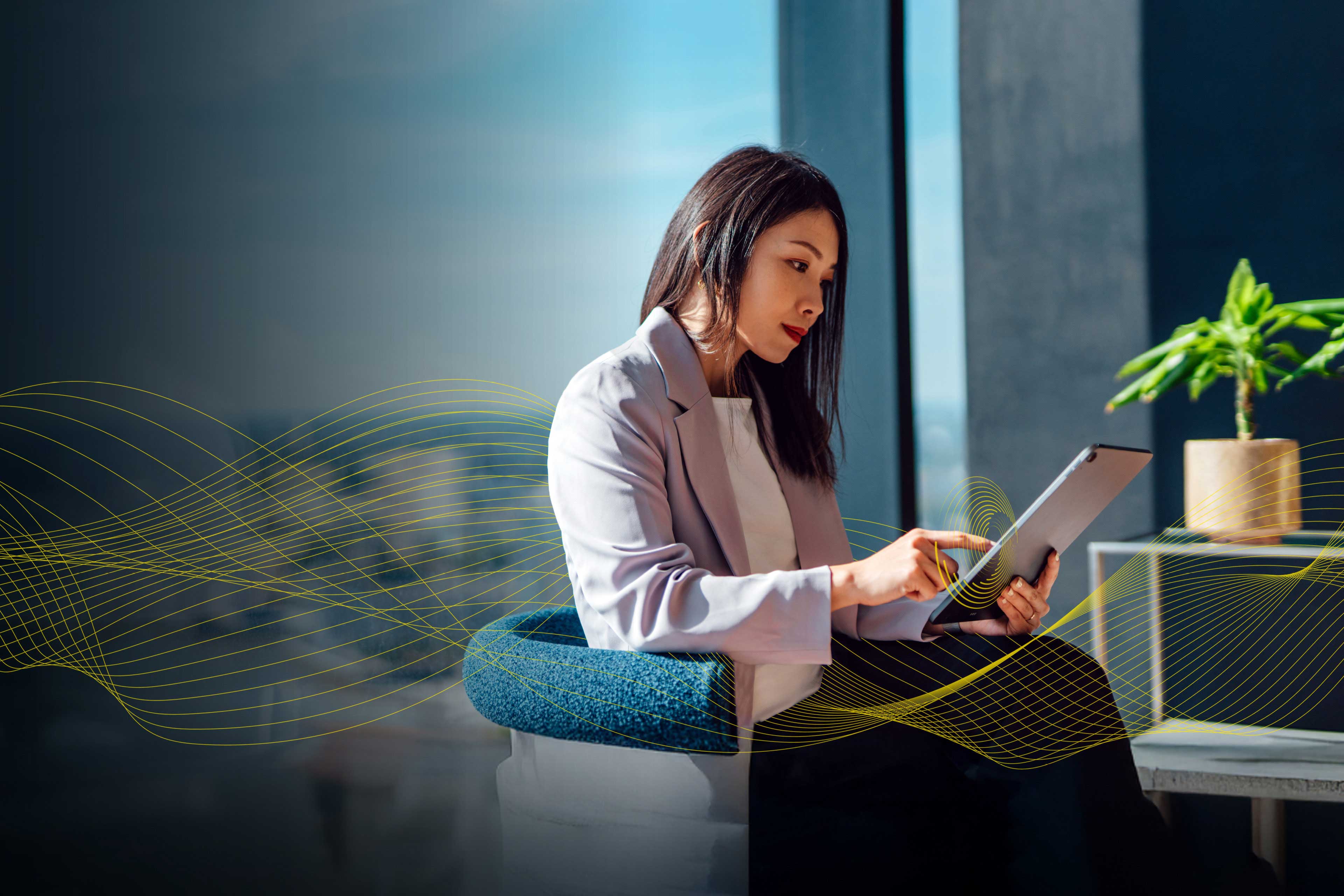 An image of a woman sitting in a chair and interacting with her tablet.