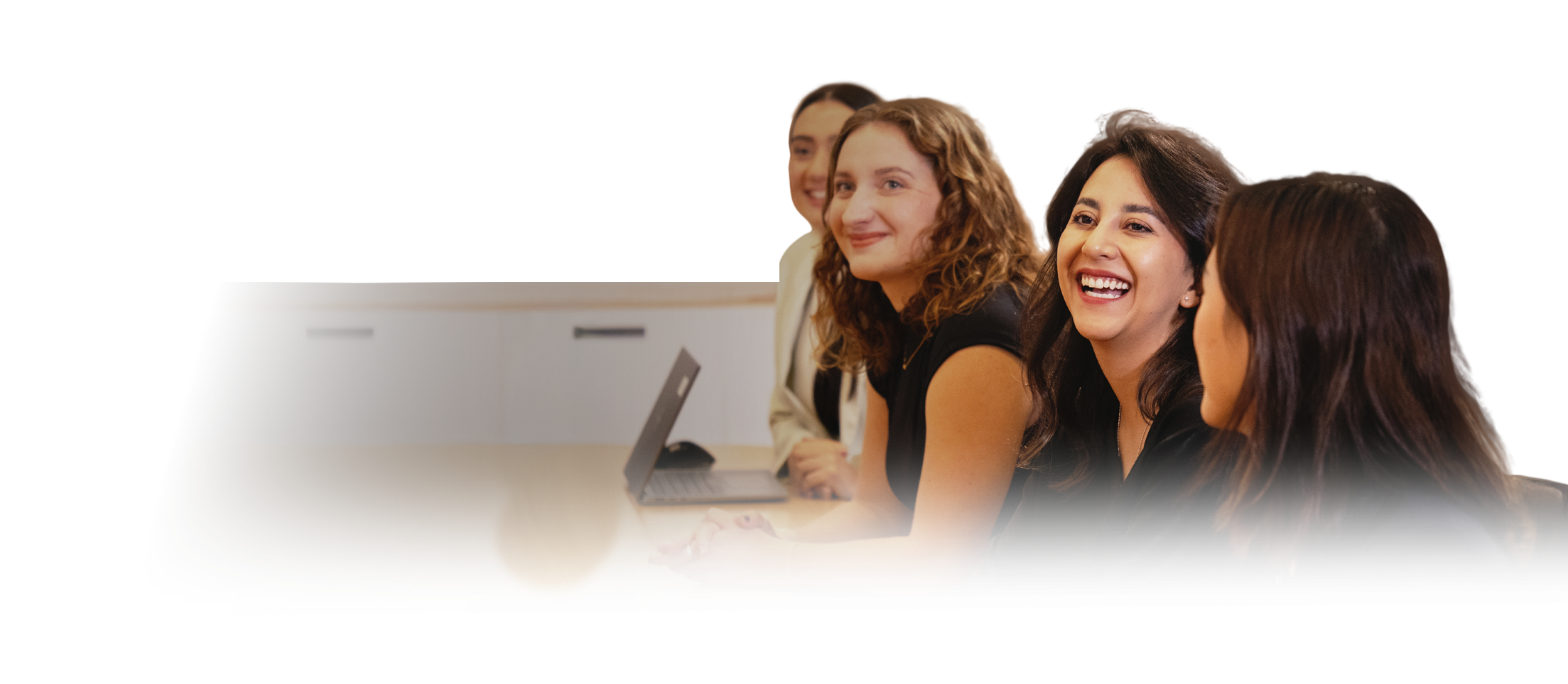 Image of young female adults sitting along a table having a discussion