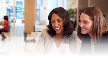 Image of two female colleagues sitting at a desk looking over content
