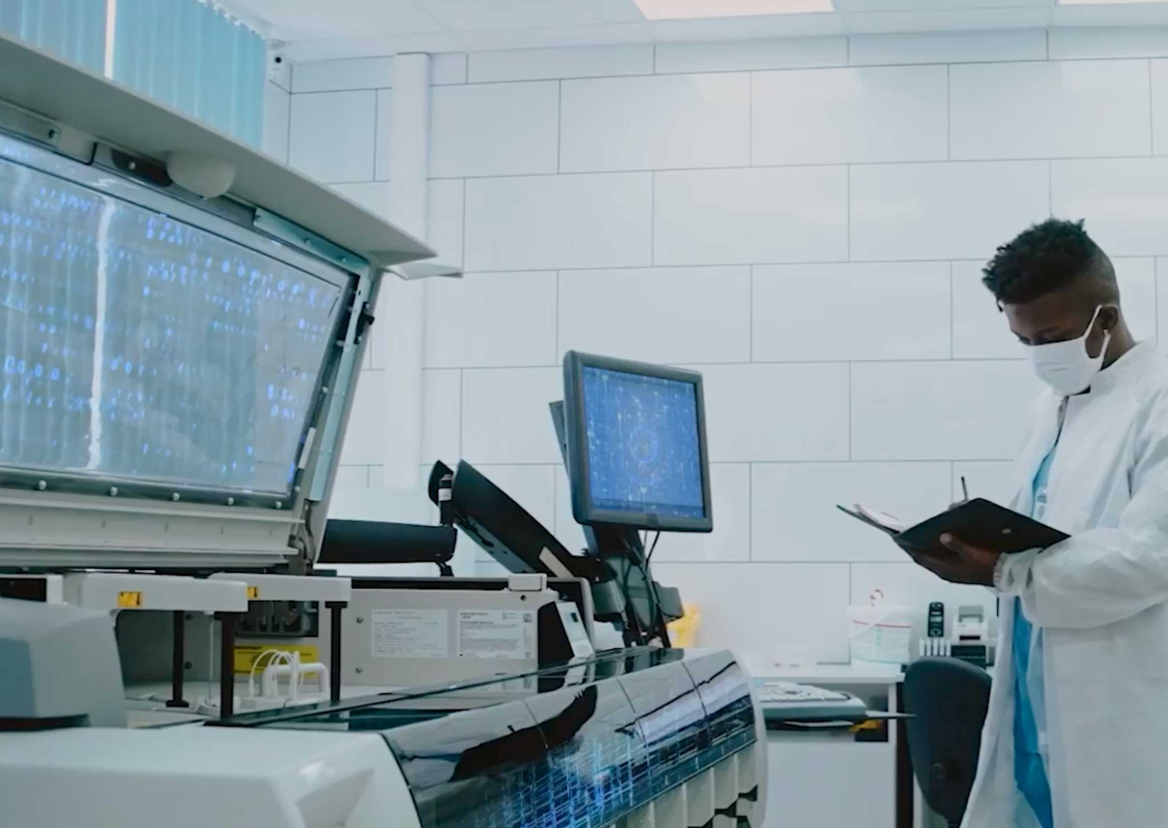 Lab technician wearing a face mask and white lab coat conducting a test.