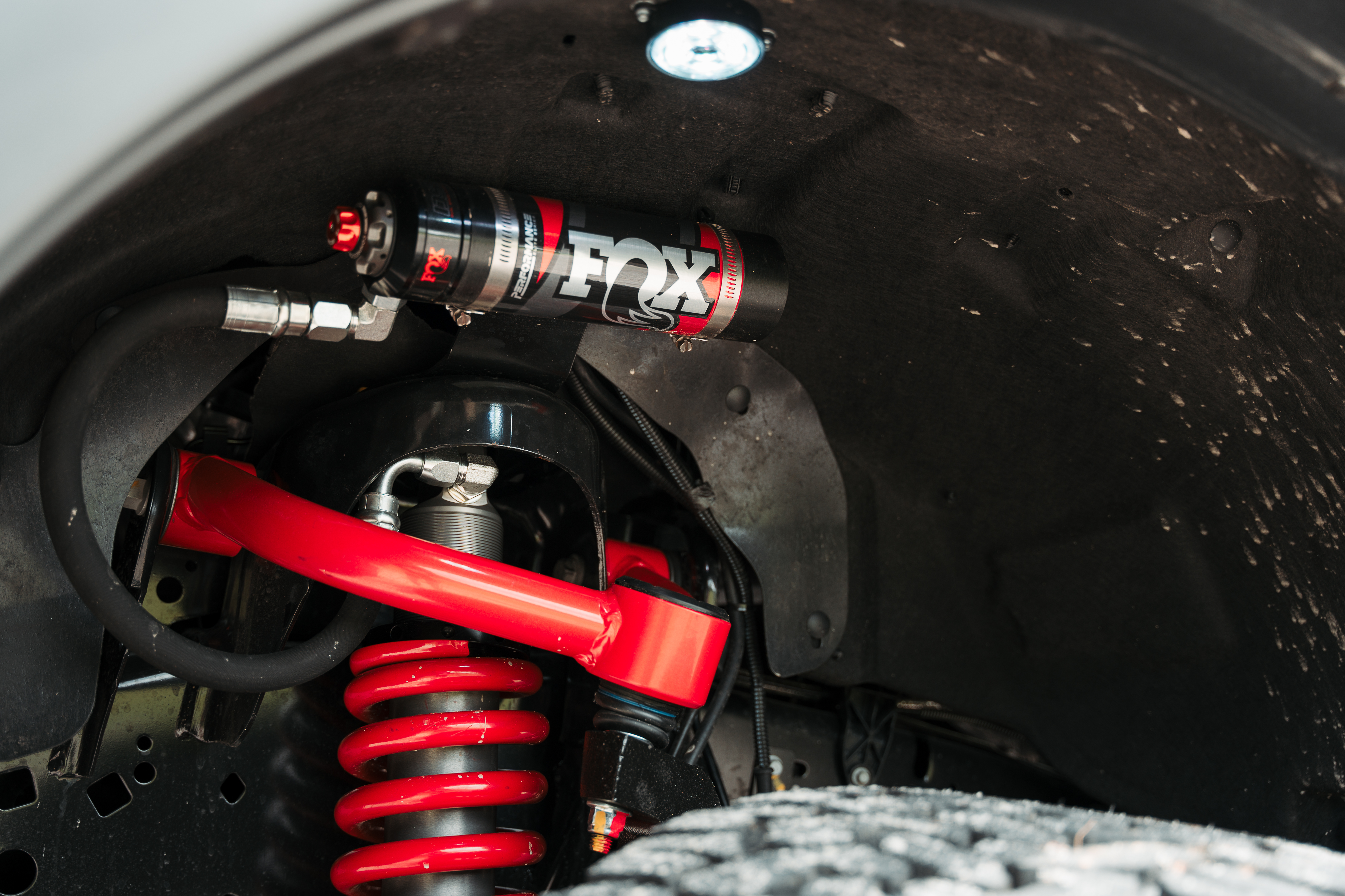 Wheel well of a black widow limited lifted truck with fox performance elite reservoir shocks and red accent color coil overs and control arm